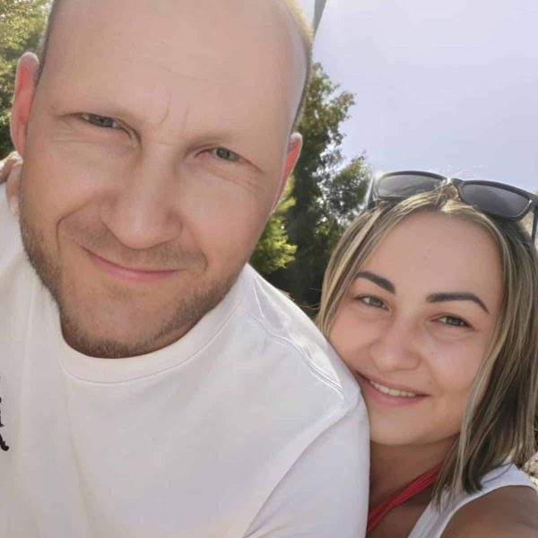 Uśmiechnięta para gospodarzy apartamentów Sweet Stay na selfie na tle drzew